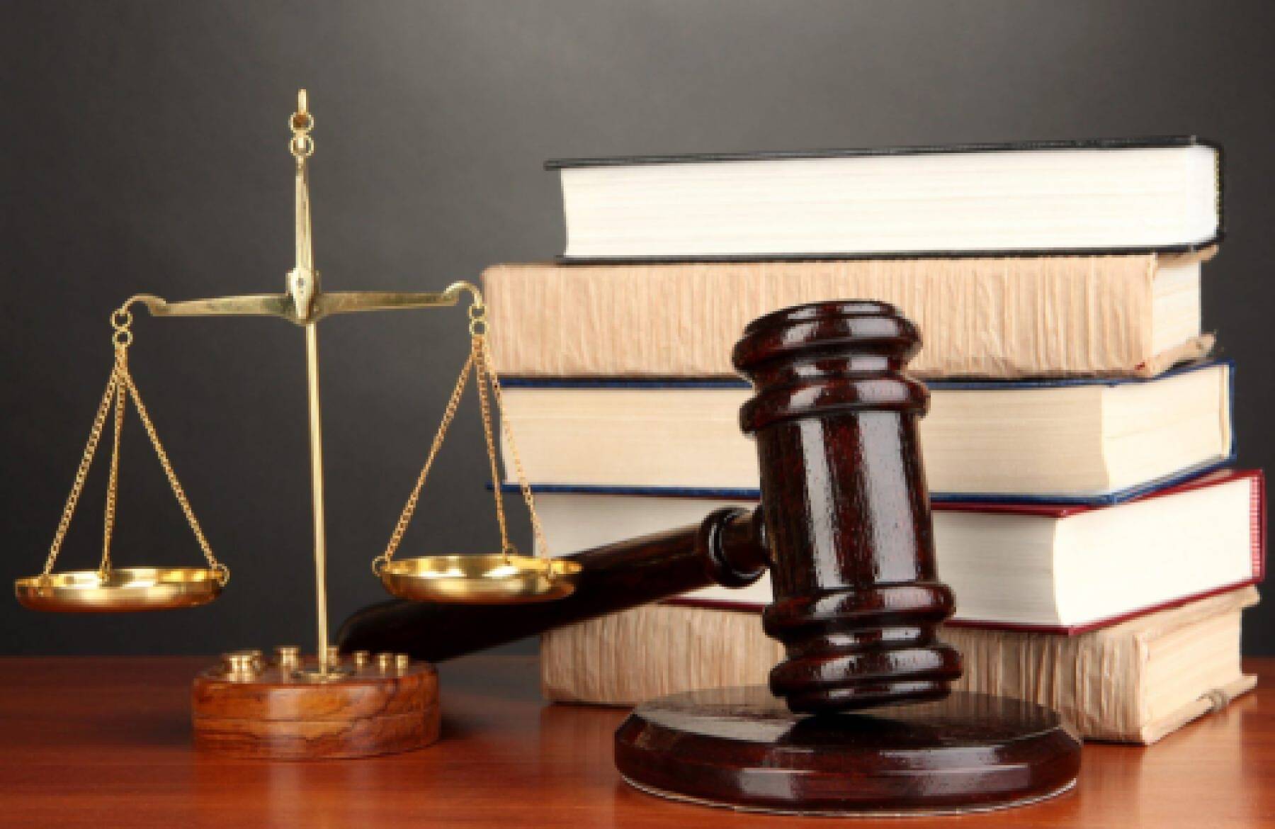 Gold scales of justice, gavel, and stacked books on top of a desk